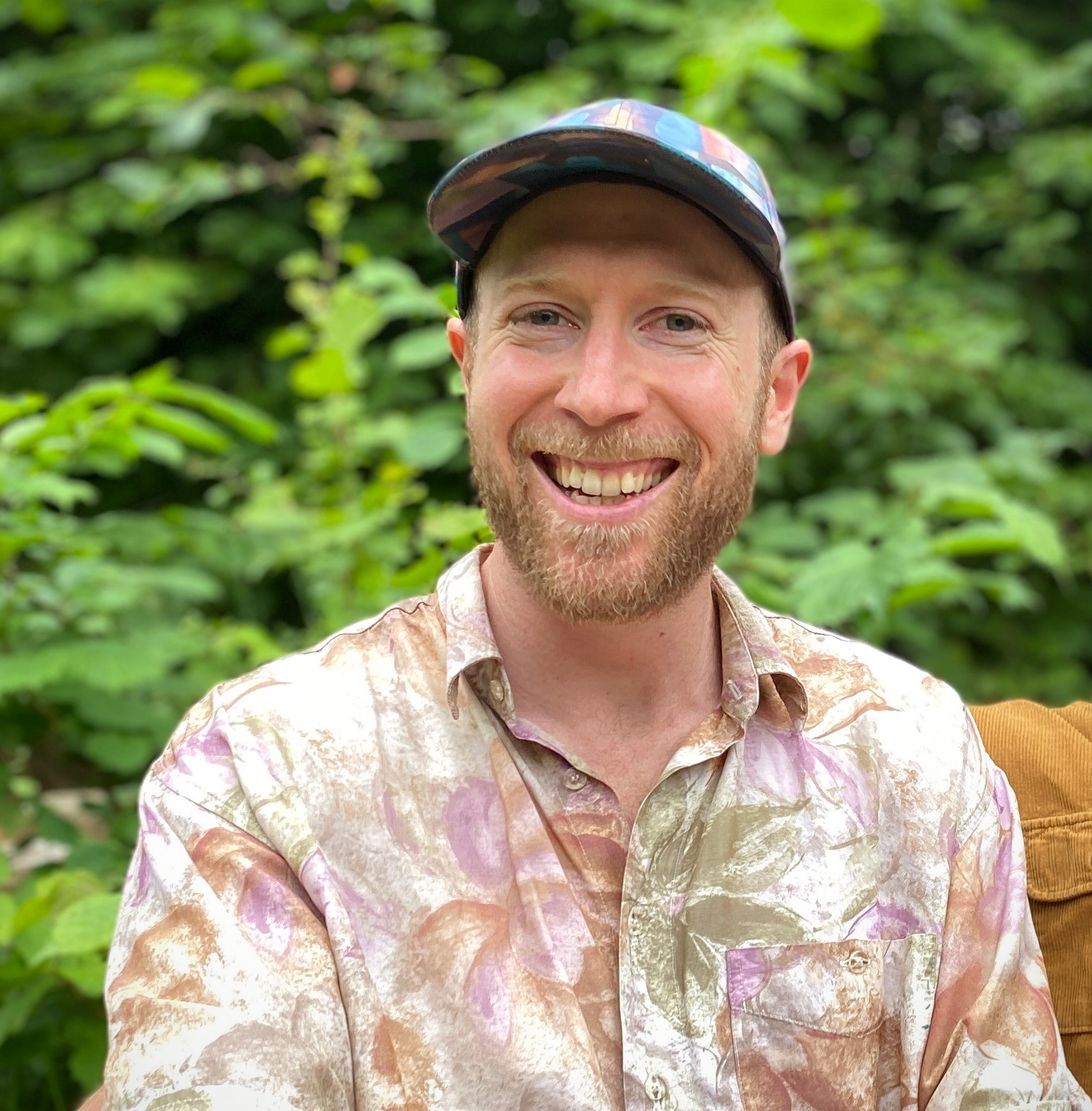 Andy Sontag smiling outdoors in a patterned shirt and cap
